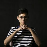 AI剧网编辑部成员头像，戴眼镜的年轻编辑在暖色灯光下专注整理ai短剧在线观看免费完整版题材条目，背景虚化柔和